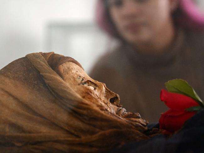 Daniela Betancourt, researcher of the National University, observes a mummy in the Jose Arquimedes Castro mausoleum museum, located at the cemetery in San Bernardo municipality, Cundinamarca department, Colombia on April 10, 2024. Clovisnerys Bejarano kneels to pray in front of the body of his mother, Saturnina, who died almost 30 years ago but whose facial features are preserved thanks to a mysterious mummification process that happens "spontaneously" in the Colombian town of San Bernardo. "For us as Sanbernardinos (mummification) has become our daily bread", explains Rocio Vergara, the person in charge of the exhibit where the bodies of Saturnina and 13 other people who also escaped decomposition for reasons not yet explained are on display. Some of them still have their eyes and fingernails. (Photo by Raul ARBOLEDA / AFP)