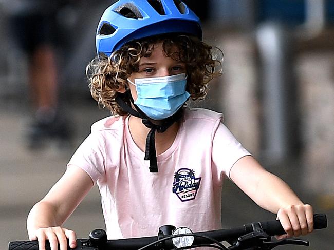 BRISBANE, AUSTRALIA - NewsWire Photos - JANUARY 10, 2021.A child wears a face mask while riding a bike at Southbank during the second day of COVID-19 lockdown in Brisbane. Greater Brisbane is under a 3-day lockdown orders after a quarantine hotel worker tested positive to the UK strain of the COVID-19 corona virus. Picture: NCA NewsWire / Dan Peled