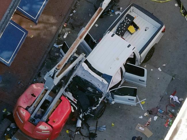 A black flag with white lettering lies on the ground rolled up behind a pickup truck that a man drove into a crowd on Bourbon Street in New Orleans, killing and injuring a number of people, early Wednesday morning, Jan. 1, 2025. The FBI said they recovered an Islamic State group flag, which is black with white lettering, from the vehicle. (AP Photo/Gerald Herbert)