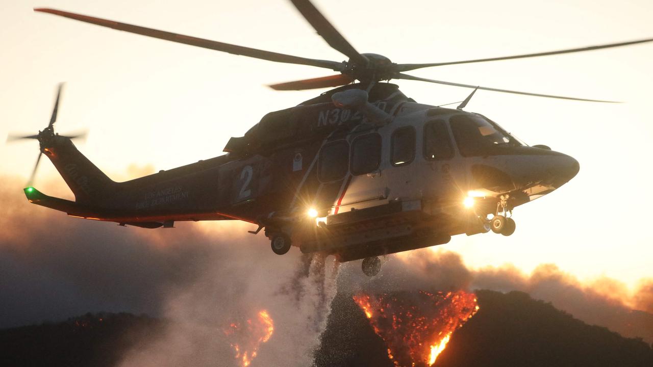 A helicopter drops water on the flames of the wind-driven Palisades on January 7. Picture: David Swanson / AFP