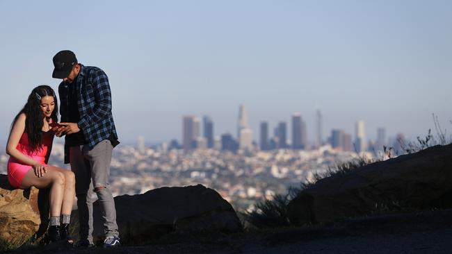 A couple check their camera with Los Angeles visible in the distance last week. Environmental Protection Agency data from March shows LA had its longest stretch of air quality rated as ‘good’ since 1995. Picture: AFP