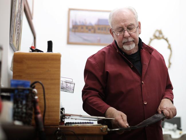 Long-time Hobart barber Paul Bromfield sharpens the edge of his cut-throat razor on a leather strop at his shop on Elizabeth St. Picture: LUKE BOWDEN