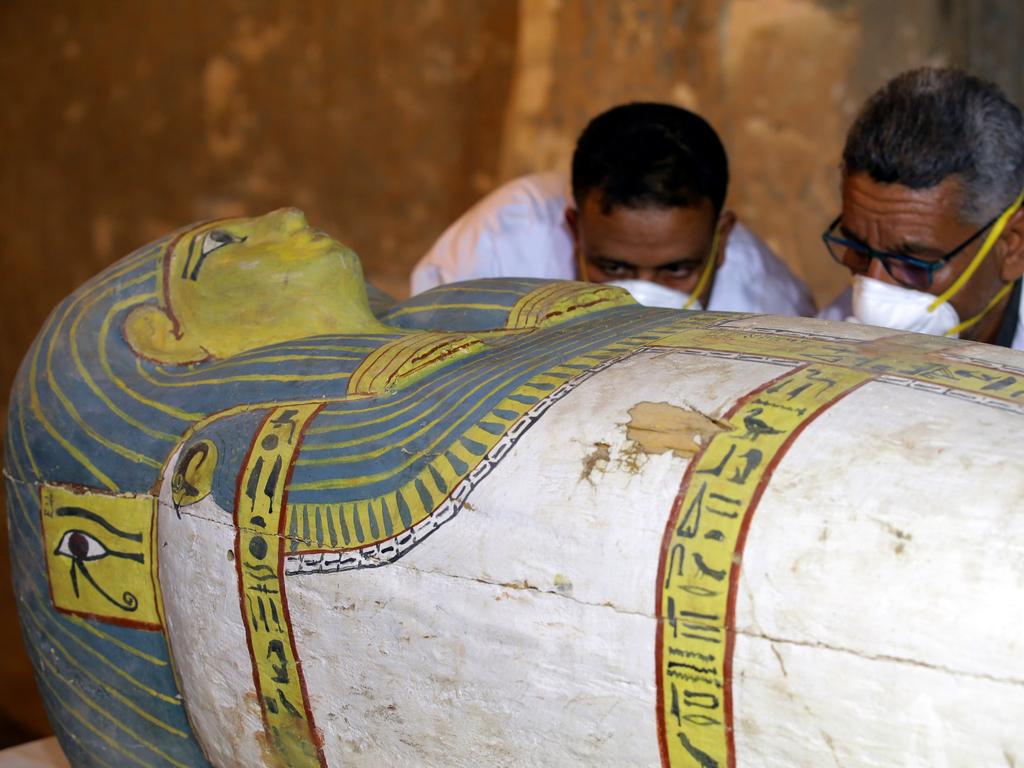 Archaeologists move the cover of an intact sarcophagus, inside a tomb in Luxor. Picture: Khaled Elfiqi