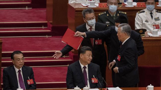 Xi Jinping and Premier Li Keqiang look on as former President Hu Jintao, centre, is taken away from the closing session of the 20th National Congress of the Communist Party of China, at The Great Hall of People. Picture: Getty Images.