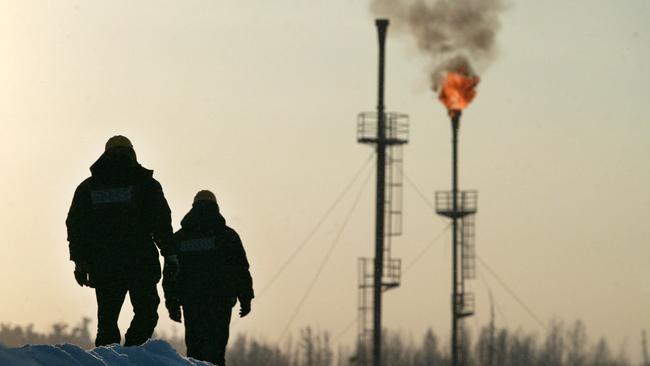 Two workers walk near a gas flare-off at the Yukos owned Mamontovskoye oil-field in the Khanty-Mansy region of the Russian Federation. Picture: Dmitry Beliakov/Bloomberg News.