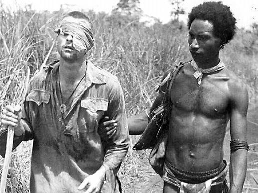 New Guinean villager Raphael Oimbari who became famous during WWII as one of the fuzzy wuzzy angels, leads wounded soldier to safety. Australian Armed Forces / Army / New Guinea / Wuzzies PNG Private George 'Dick' Whittington (L)