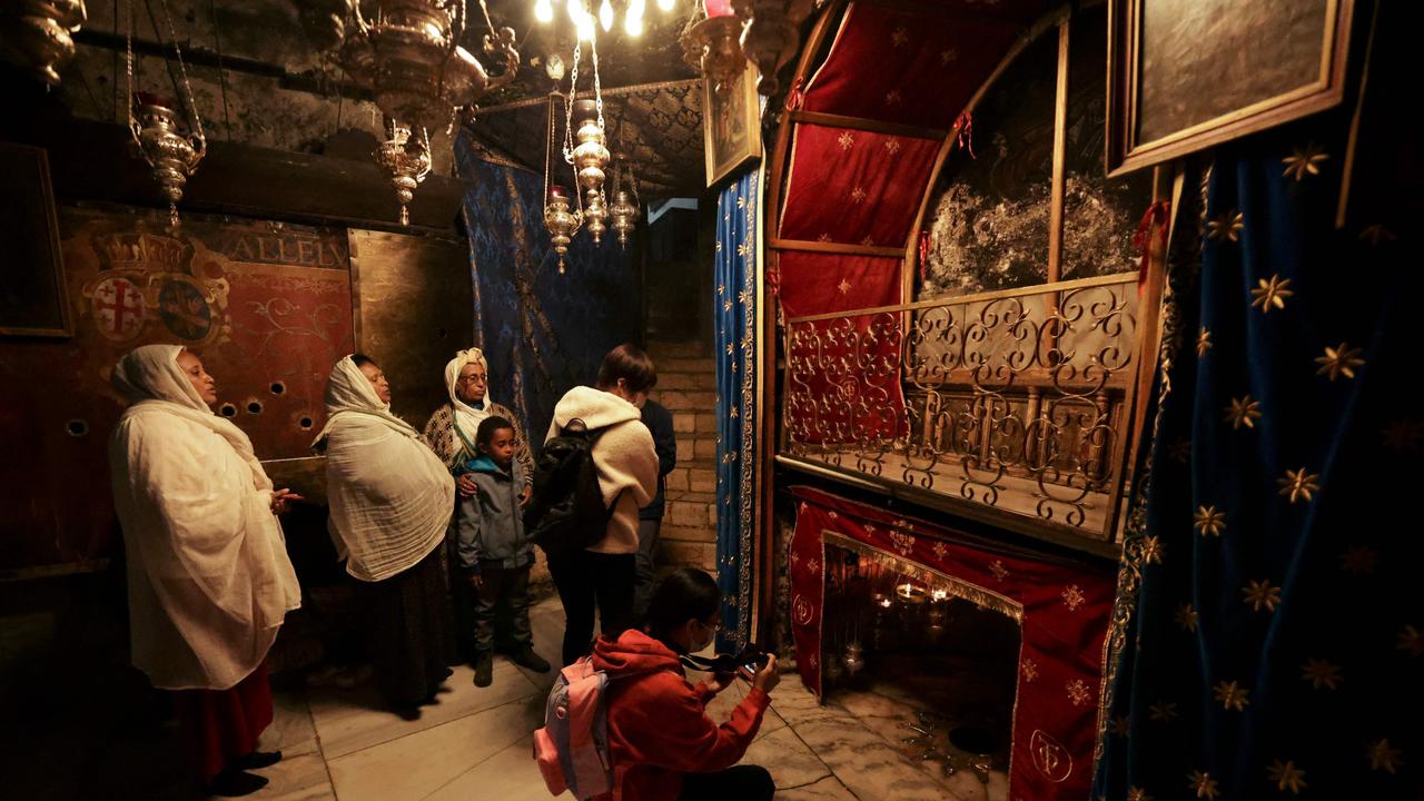 Pilgrims and tourists pray at the grotto, believed to be the site of the birth of Jesus, at the Church of the Nativity in the biblical West Bank city of Bethlehem on December 22.
