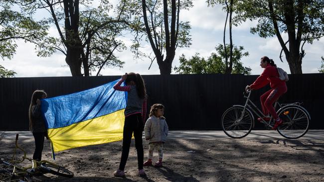 Girls hold up a Ukrainian flag to passers-by in the reclaimed city of Izyum, Donetsk, Ukraine. Picture: Getty Images