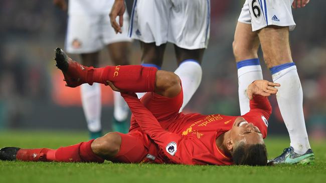 Liverpool's Brazilian midfielder Roberto Firmino lies injured on the pitch.