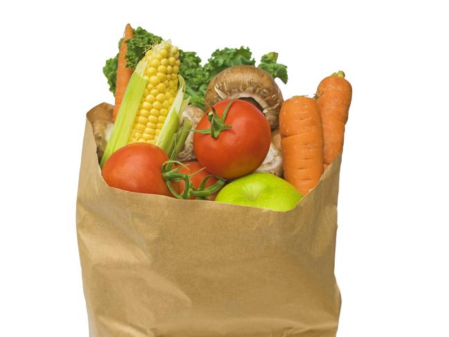 Healthy fruit and vegetables in a brown paper bag, isolated on a white background