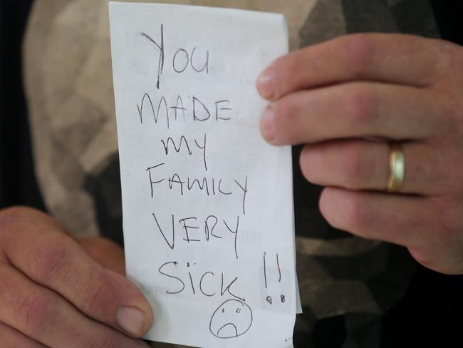 Ross Paull places a note on the door of the bakery after his wife and daughter fell ill. Picture: John Grainger