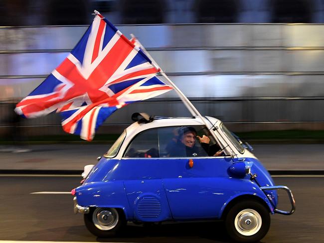 -- AFP PICTURES OF THE YEAR 2020 --  A man waves Union flags from a BMW Isetta as he drives past Brexit supporters gathering in Parliament Square, in central London on January 31, 2020, the day that the UK formally leaves the European Union. - Britain on January 31 ends almost half a century of integration with its closest neighbours and leaves the European Union, starting a new -- but still uncertain -- chapter in its long history. (Photo by DANIEL LEAL-OLIVAS / AFP)