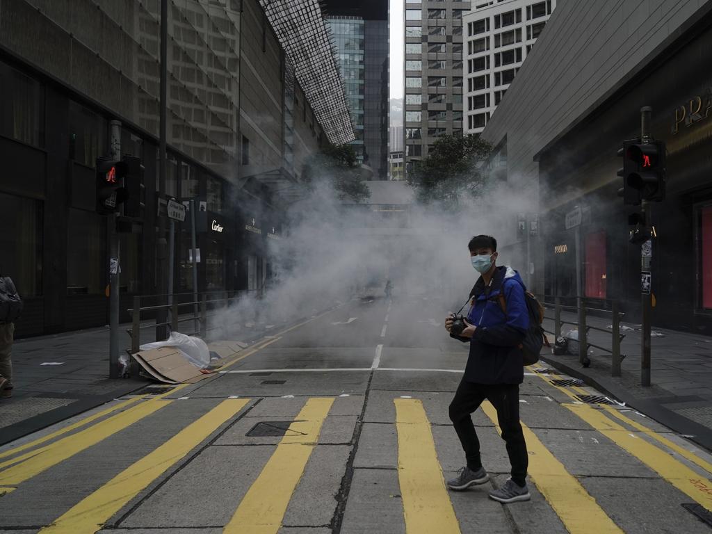 A man walks past as police use tear gas on protesters during a violent anti-government protest on Sunday. Picture: AP Photo/Kin Cheung