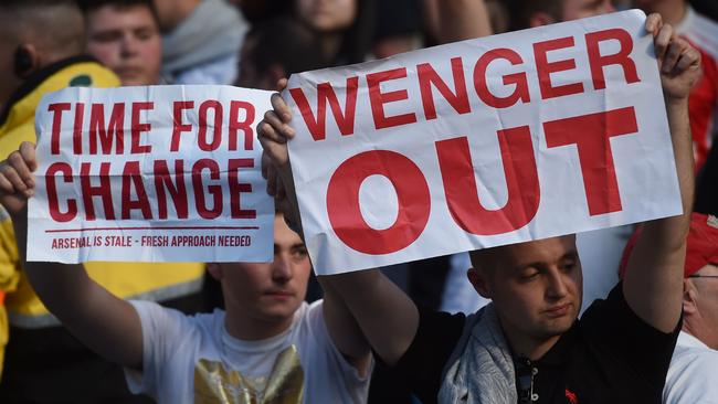 Arsenal fans hold up signs calling for the resignation of Arsenal's French manager Arsene Wenger after the English Premier League football match between Manchester City and Arsenal at the Etihad Stadium in Manchester, north west England, on May 8, 2016. / AFP PHOTO / PAUL ELLIS / RESTRICTED TO EDITORIAL USE. No use with unauthorized audio, video, data, fixture lists, club/league logos or 'live' services. Online in-match use limited to 75 images, no video emulation. No use in betting, games or single club/league/player publications. /