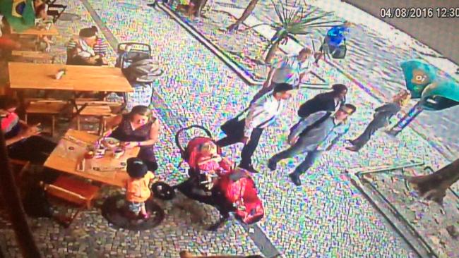 Two of the thieves (pictured centre of the screen) waited outside the cafe while their accomplice worked inside.