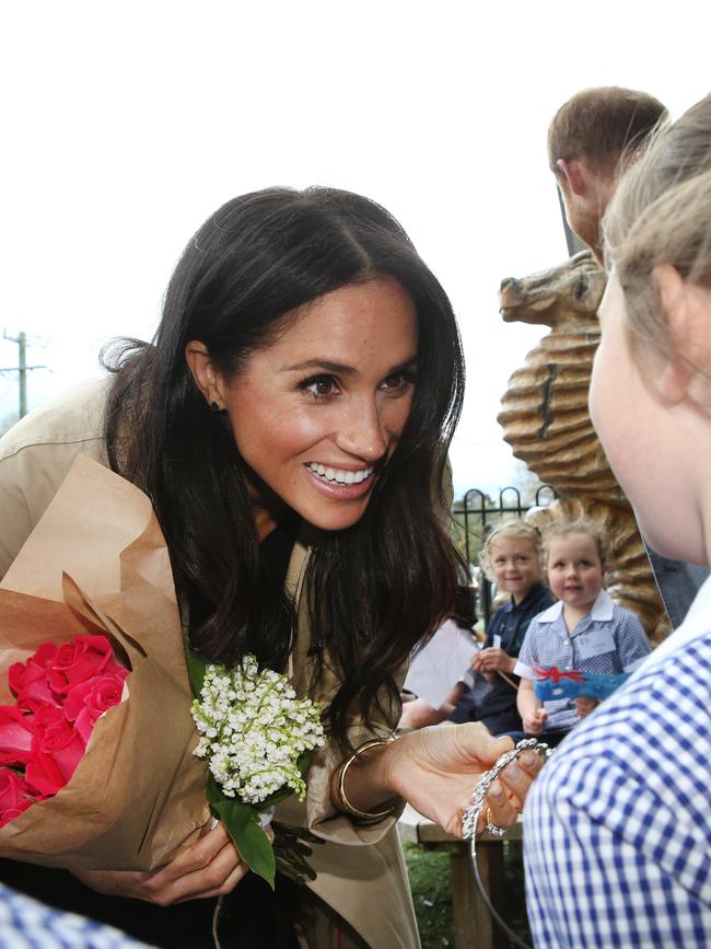 Meghan Markle is handed a tiara and flowers by a little girl in Melbourne. Picture: David Caird