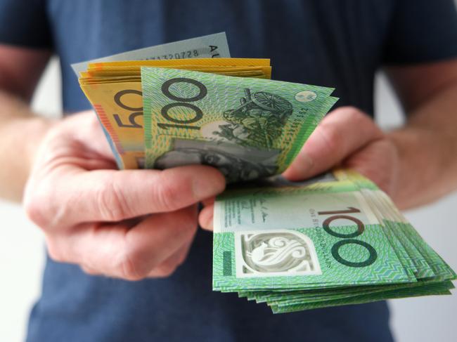 A man counting Australian dollar bills. A picture that describes buying, paying, handing out money, or showing money. Australian cash money generic