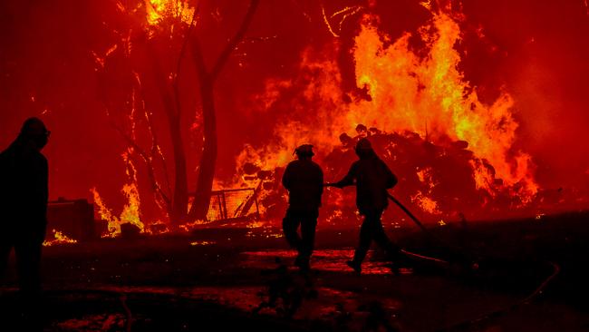 Firefighters face the roaring flames and intense heat of the Gospers Mountain fire on December 21 as it moved rapidly towards Kurrajong from Bilpin along the Bells Line of Rd. Picture: Matrix