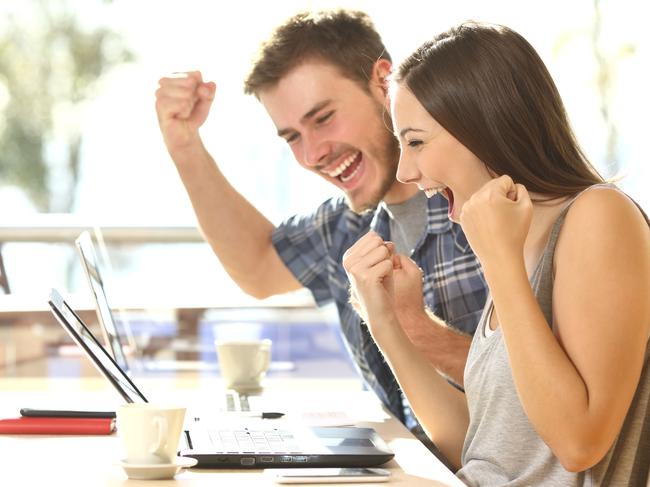 Group of two young euphoric students watching exam results in a laptop in a table of an university campus bar