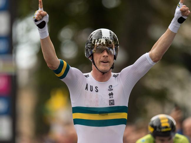 TOPSHOT - Australia's Rohan Dennis (C) gestures as he passes Slovenia's Primoz Roglic (R) and crosses the line to win the Elite Men Individual Time Trial, over 54 kms from Northallerton to Harrogate, at the 2019 UCI Road World Championships in Harrogate, northern England on September 25, 2019. (Photo by OLI SCARFF / AFP)