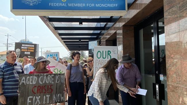 Member for Gaven Meaghan Scanlon and Queensland Senator Murray Watt slide their aged care petition under the door of Moncrieff LNP MP Angie Bell.