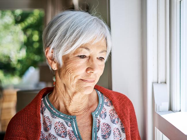 Senior woman lost in thought while looking out through her living room window at home. Picture: Getty Images