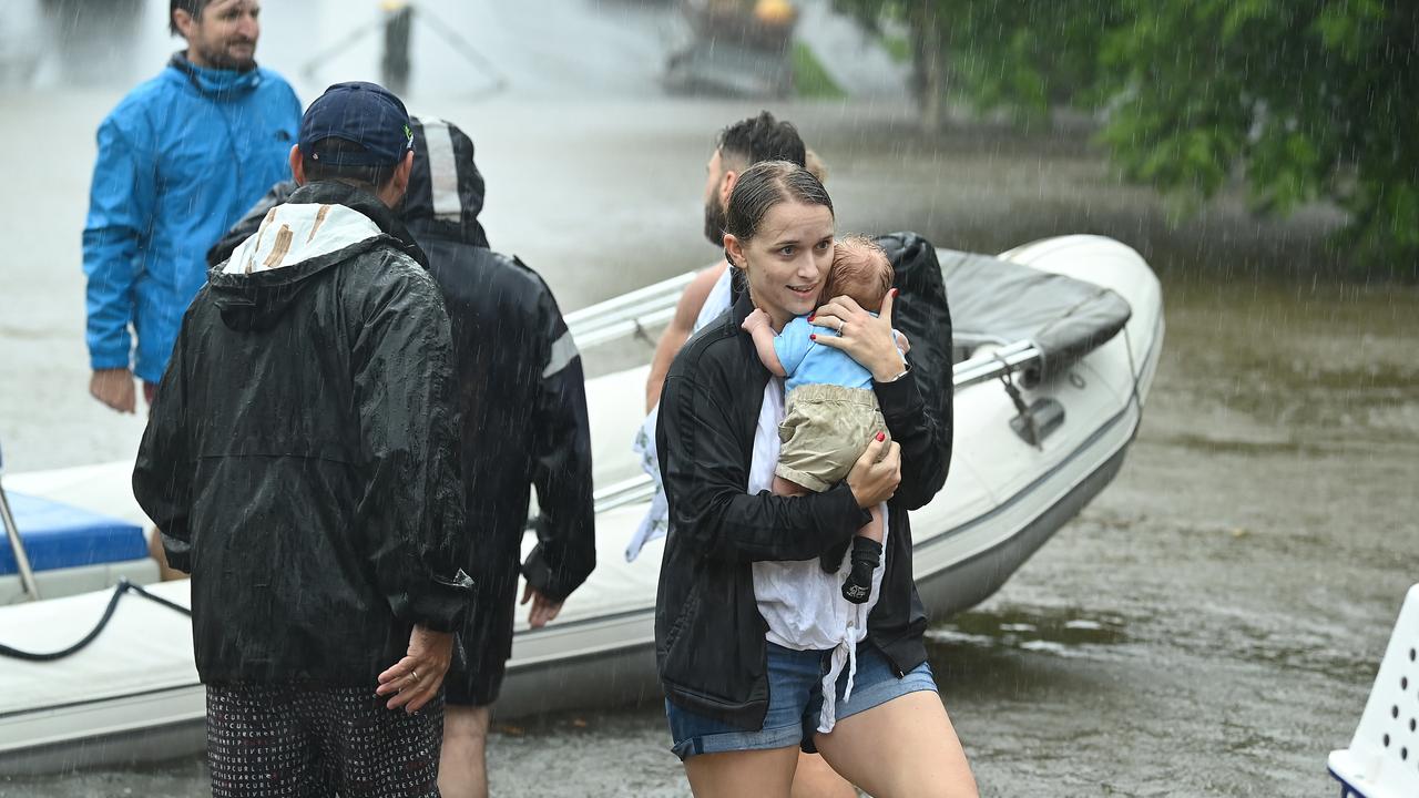 A mother carries her baby through flood waters in Brisbane. Picture: Lyndon Mechielsen/The Australian