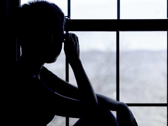 teenager girl looks outside into the window in the small hostel room with bunk bed