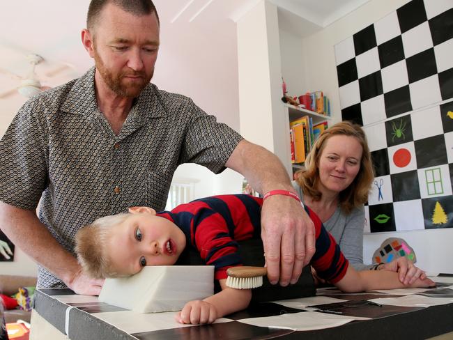 David and Ina Mills give son Roki, 3, patterning therapy at their Newport home. Picture: Troy Snook