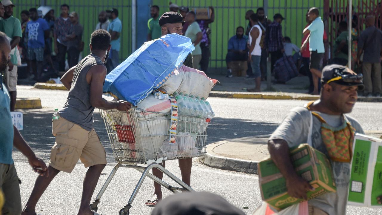 A man pushes a shopping trolley on the street as looters raid Port Moresby. Picture: AFP