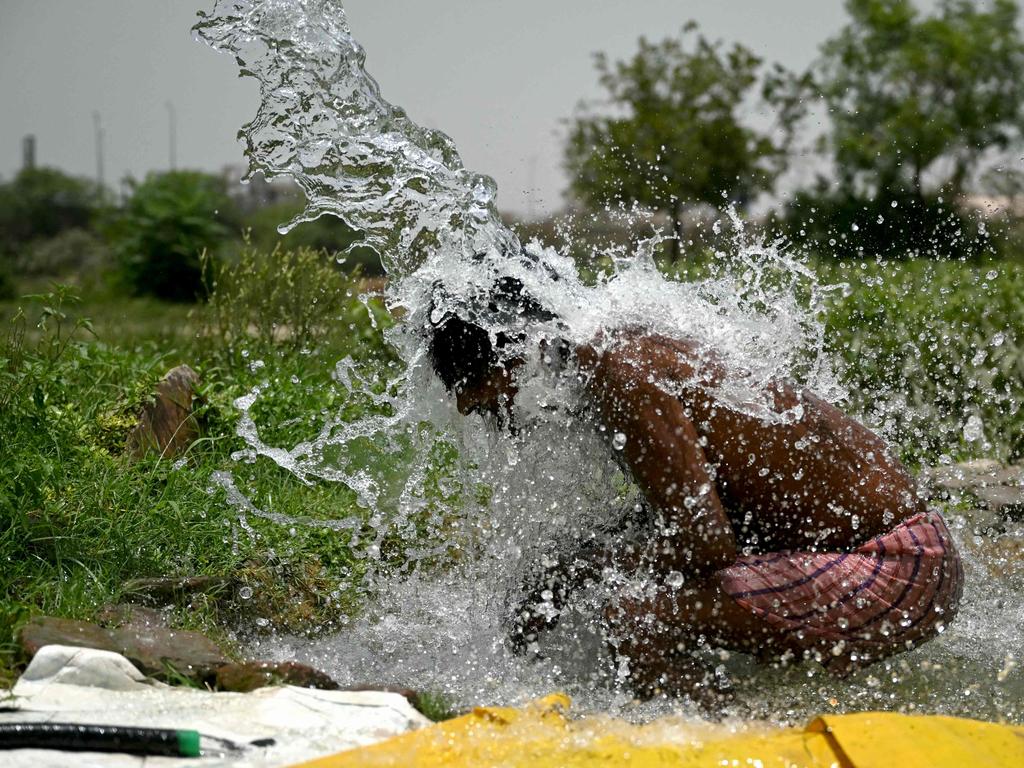 A man takes a shower under water pouring from a pipe along the Yamuna flood plains on a hot summer afternoon in New Delhi.