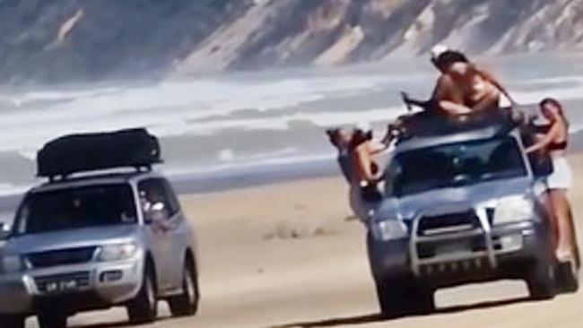 Toyota LandCruiser travelling with five people hanging on outside the vehicle, as another four-wheel drive drove alongside it.