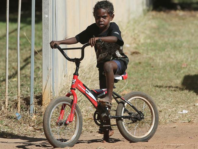 Indigenous boy Lewis Kooloika rides his bike through the dusty streets of Aurukun. Picture: Brendan Radke