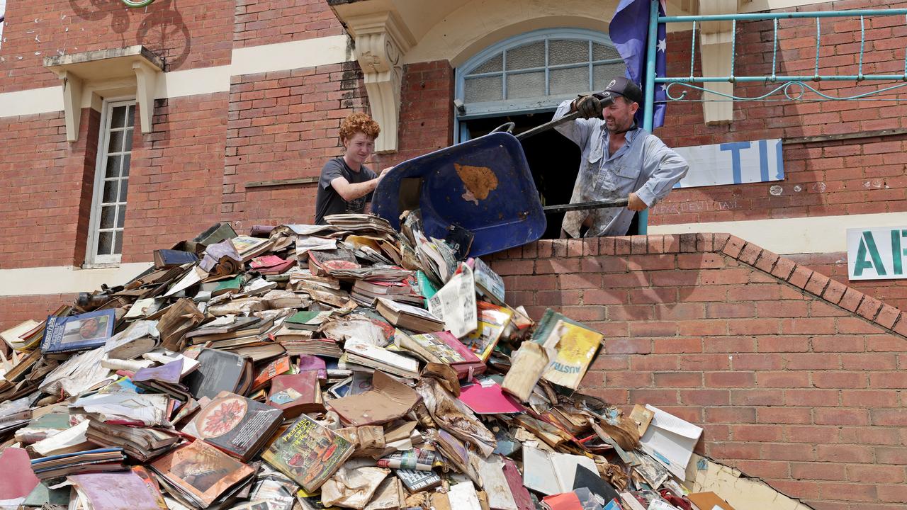 Brodey and Gary Rossington throw out damaged books from Books and Stuff onto the footpath. Picture: Toby Zerna