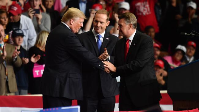 Donald Trump shakes hands with Republican congressional candidate in North Carolina Mark Harris, right, flanked by fellow congressional candidate Ted Budd, during the Charlotte rally. Picture: AFP