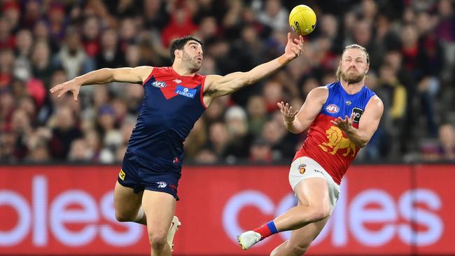 Christian Petracca gets his hand on the ball in front of Lion Daniel Rich. Picture: Quinn Rooney/Getty Images