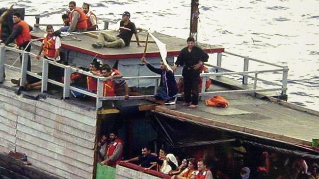 OCTOBER 9, 2001: Asylum-seeking refugees, one waving a white flag, on an Indonesian boat in the Indian Ocean before being rescued by sailors from HMAS Adelaide.