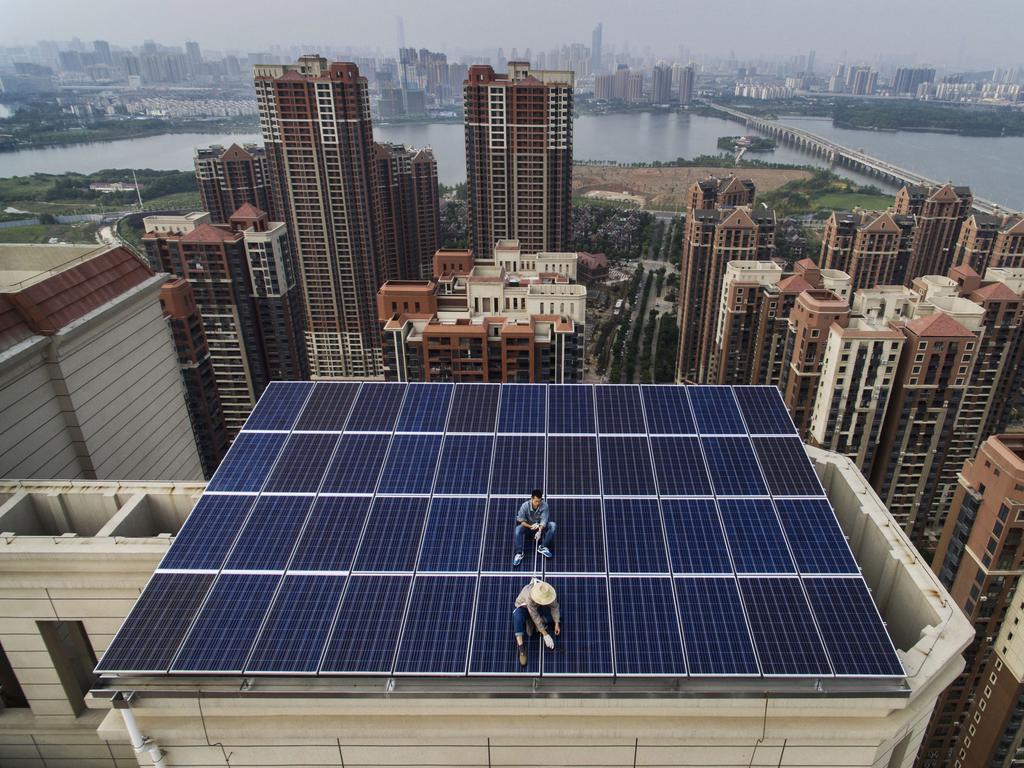 Workers from the Wuhan Guangsheng Photovoltaic Company install solar panels on a building in China. Picture: Kevin Frayer / Getty Images