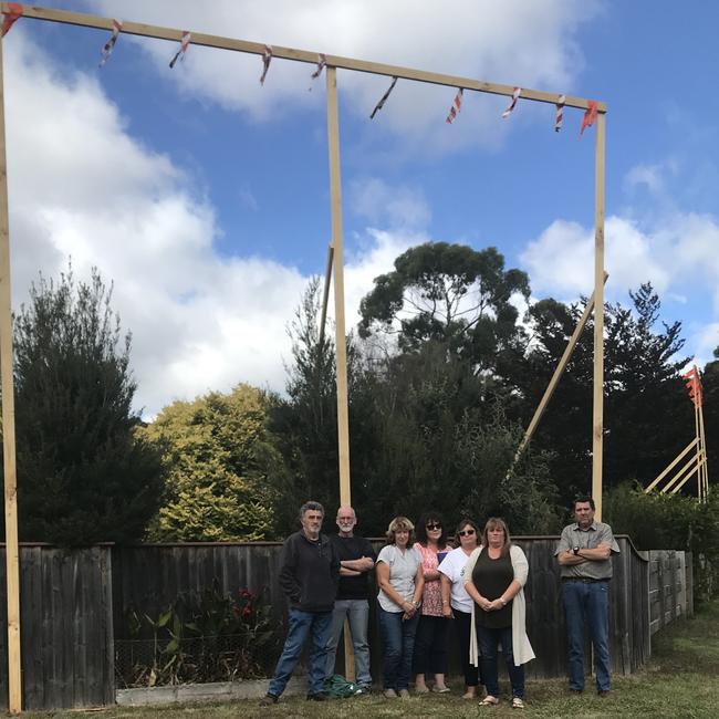 Leith residents under a timber structure which shows how high the proposed overpass would be outside Tony Downey's property