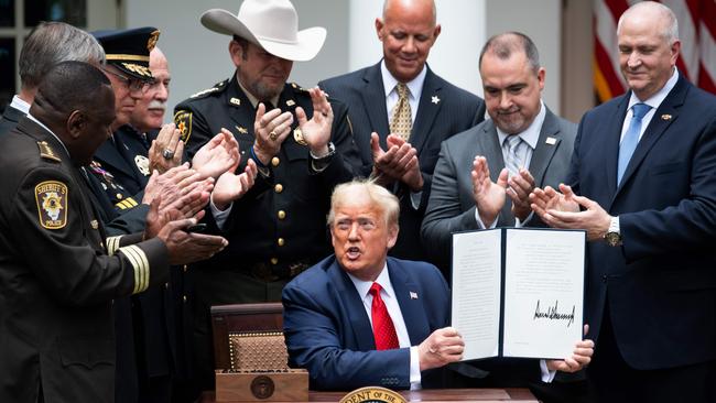 US President Donald Trump shows his signature on an Executive Order on Safe Policing for Safe Communities, in the Rose Garden of the White House in Washington.