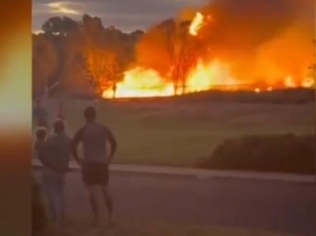 Residents watch on as flames engulf nearby wetlands.