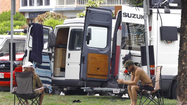 Residents stroll past some rubbish on the Burleigh Esplanade, while campers seem to be taking advantage of free parking spots and setting up camp on the Esplanade. Picture: Tertius Pickard