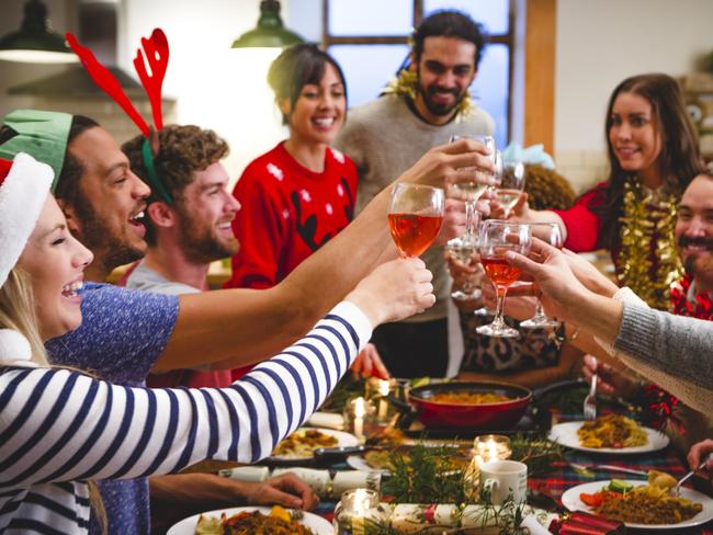 CAREERS: Group of friends toast together with their glasses of wine. They are sitting around a table with food and christmas crackers in from of them. Wearing party hats and novelty jumpers, tinsel ext they celebrate together.