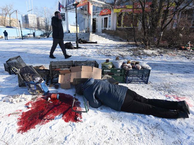 A man talks on the phone while walking past bodies of people lying on the ground, killed as a result of a missile strike, amid the ongoing Russian-Ukrainian conflict. Picture: AFP