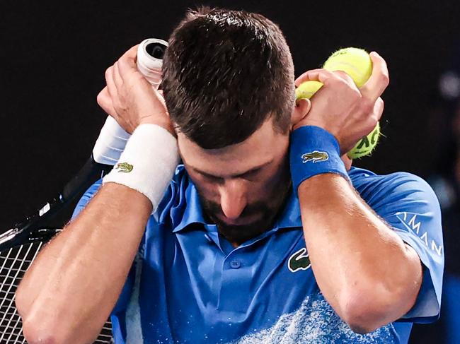 TOPSHOT – Serbia's Novak Djokovic covers his ears as he reacts to spectators making noise while he was about to serve against Czech Republic's Jiri Lehecka during their men's singles match on day eight of the Australian Open tennis tournament in Melbourne on January 19, 2025. (Photo by DAVID GRAY / AFP) / -- IMAGE RESTRICTED TO EDITORIAL USE – STRICTLY NO COMMERCIAL USE --