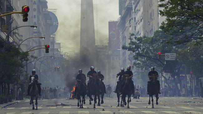 FILE - In this Dec. 20, 2001 file photo, mounted police charge anti-government demonstrators in Buenos Aires, Argentina, after the South American nation had just defaulted on more than $100 billion in foreign debt, banks were shuttered, the economy was in ruins and streets were filled with pot-banging protesters whose chants of "throw them all out" sent five presidents packing. As Argentines closely watch the 2015 financial turmoil in Greece, recalling their worst crisis 14 years ago, the architect of the South American country’s recovery says the European nation should renegotiate its debt. (AP Photo/Walter Astrada, File)