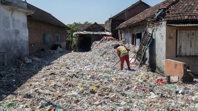 A worker sifts through imported rubbish in East Java. Picture: Graham Crouch