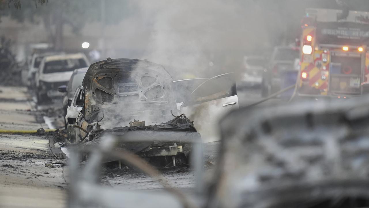 Vehicles are damaged as authorities work the scene where a small plane crashed into a San Diego neighbourhood. Picture: AP/Gregory Bul.
