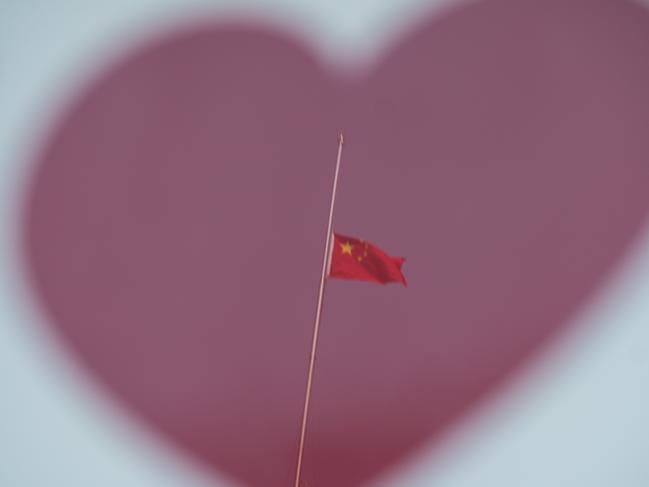 A reflector shows The Chinese national flag flies at half-mast at the Bund to mourn victims of COVID-19 on April 04, 2020 in Shanghai, China. Picture: Getty