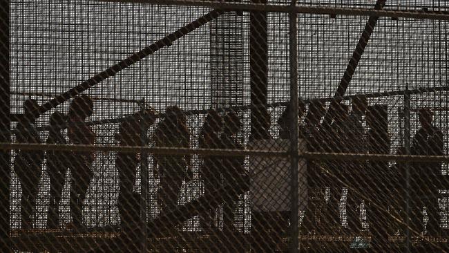 Migrants wait along the border wall to surrender to US Customs and Border Protection agents for immigration and asylum claim processing upon crossing the Rio Grande river into the US in El Paso, Texas. Picture: AFP